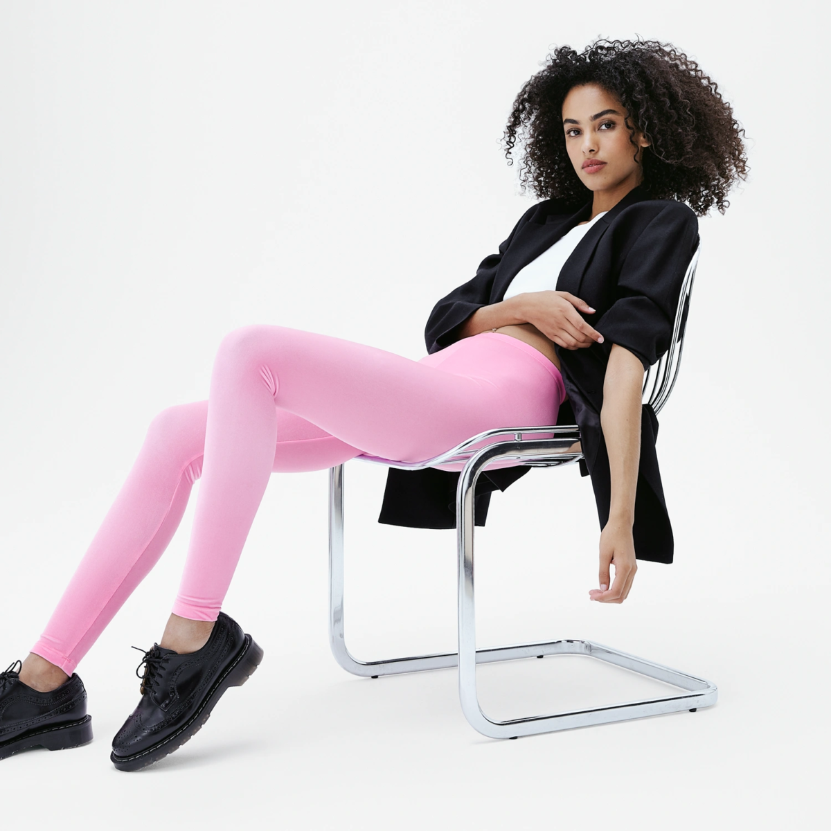 Look mode femme avec legging velours rose pastel, veste noire et derbies