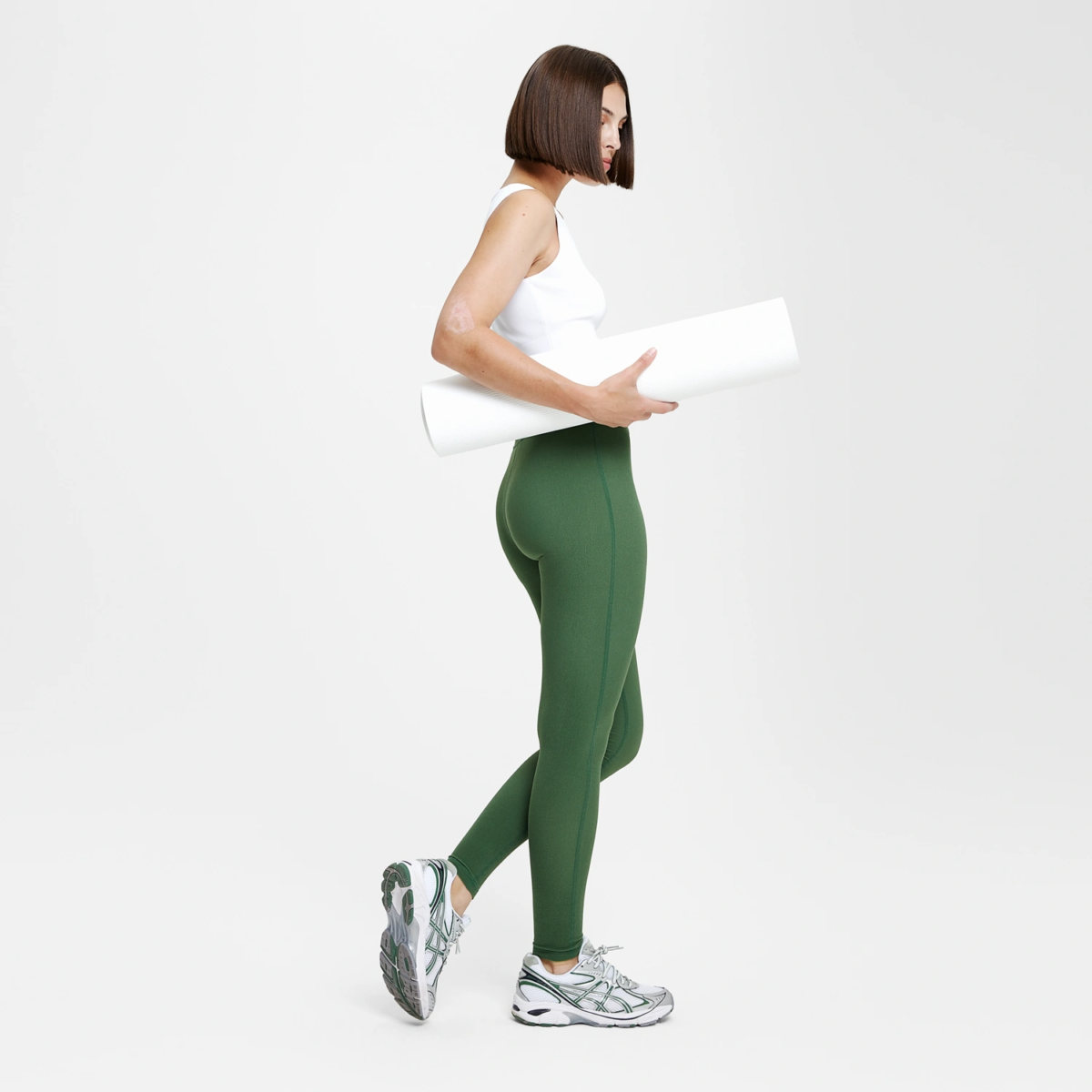 Profil femme en legging yoga vert forest green coupe sportive, look sport chic avec tapis de yoga