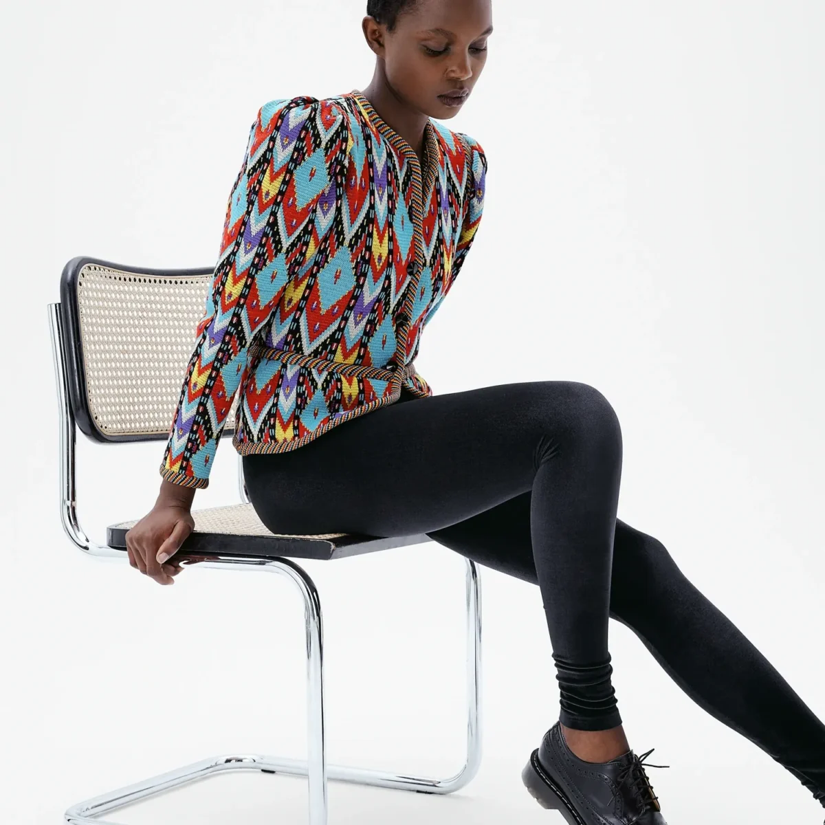 Legging en velours noir Black Swan porté avec un haut multicolore, détail des jambes en position assise